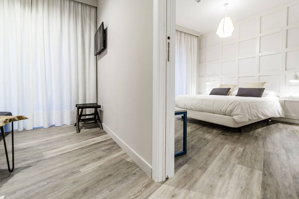 A modern hotel room with a large bed, a desk, and a TV.