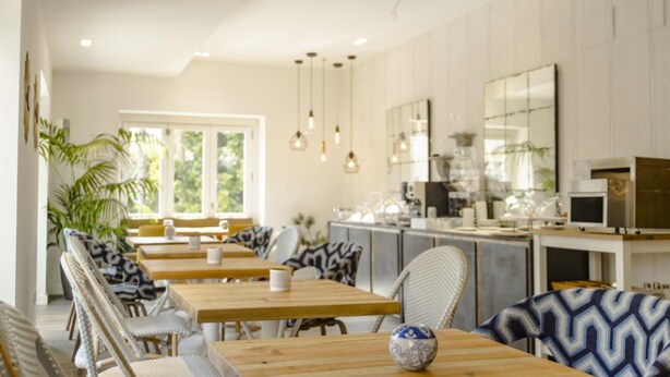 A modern kitchen with wooden countertops, a built-in oven, and a microwave. There are hanging pendant lights and a large window providing natural light.