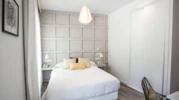 Un dormitorio moderno con una cama grande, lámparas de noche, una lámpara colgante y un armario.