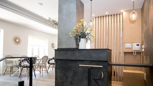 A modern reception area with a dark reception desk, a vase of flowers, and a wooden slatted wall.