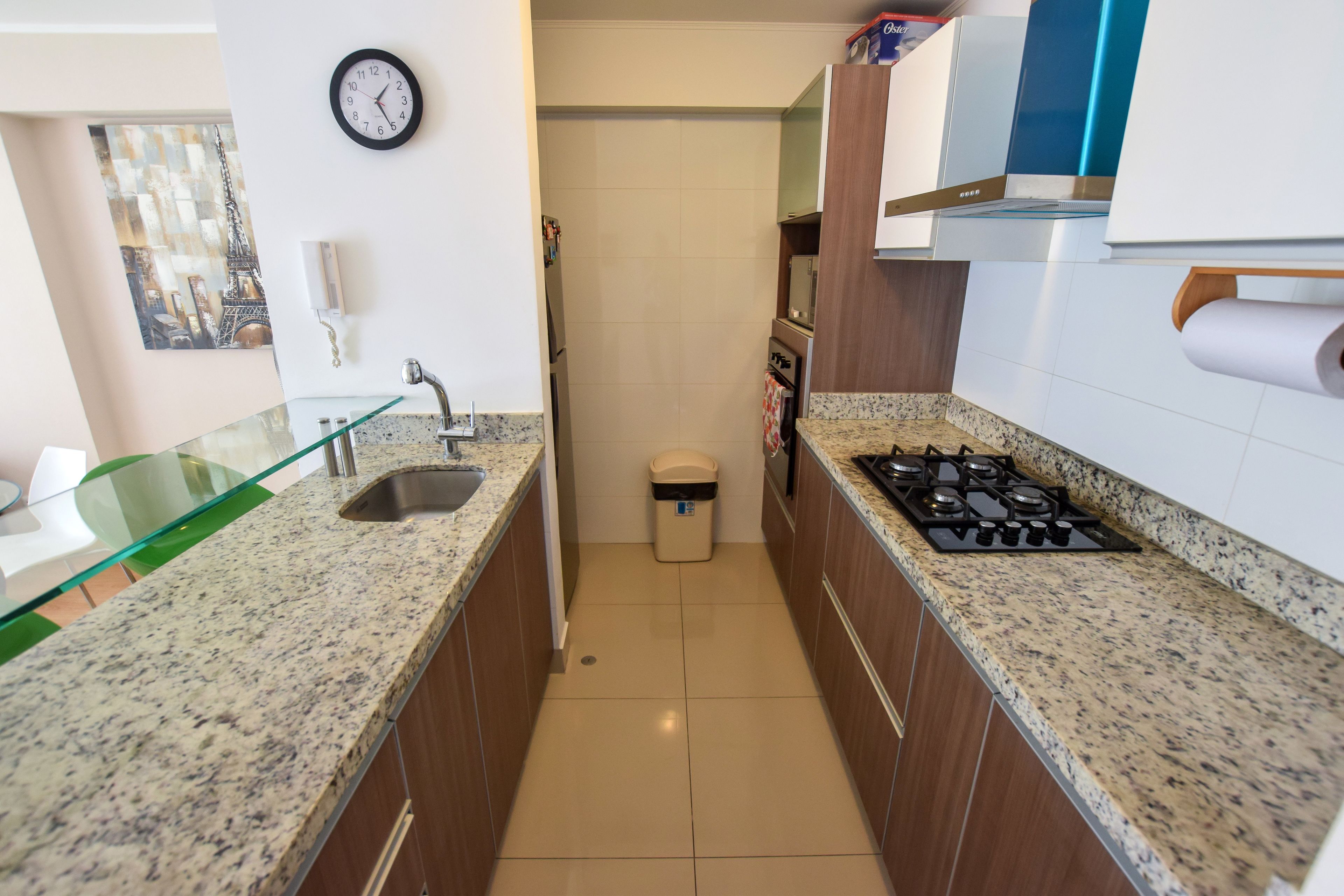 Cocina compacta con encimeras de granito, pileta de acero inoxidable, estufa a gas y un bote de basura.