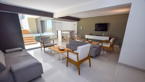 A modern living room with a grey sofa, a coffee table, and a dining area with a TV. - Miraflores Nest Upper Pardo (Lima)