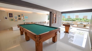 A modern indoor pool area with a pool table, framed pictures on the wall, and a view of the outdoors. - Miraflores Nest Upper Pardo (Lima)