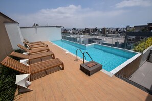 A rooftop pool with wooden loungers and a glass barrier. - Miraflores Nest Upper Pardo (Lima)