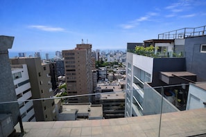 Zona urbana con edificios de gran altura, incluyendo un rascacielos beige destacado y una estructura moderna con jardín en la azotea.