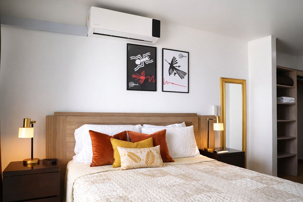A hotel room with a bed, two wall art pieces, a wardrobe, and a bedside lamp.