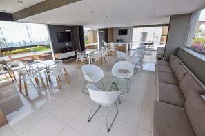 A modern living room with a glass coffee table, white chairs, a beige sofa, and a flat-screen TV mounted on the wall. - Miraflores Nest Upper Pardo (Lima)