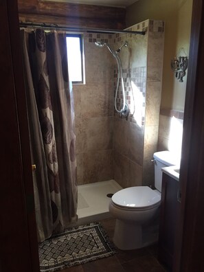 A bathroom with a shower, toilet, and a small window. - Bighorn Lodge and Angler (Fort Smith)