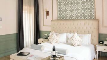 Habitación de hotel con una cama grande, una mesita de noche, un escritorio pequeño, una silla, un ventanal con cortinas y un panel decorativo en la pared.