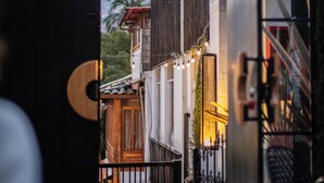 An entrance with a metal gate, a staircase, and a view of a building with a wooden door and string lights. - Illa Experience Hotel (Quito)