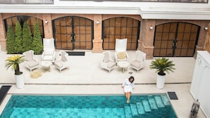 A rooftop pool area with lounge chairs, a person walking by, and traditional Chinese opera posters on the wall. - Illa Experience Hotel (Quito)