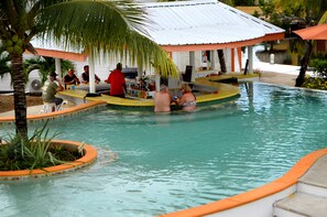 A pool area with a covered bar and lounge seating. - SailFish Resort (Placencia)