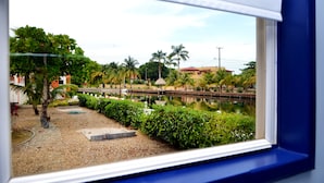 Vista de una masa de agua tranquila con un puente, palmeras y un edificio al fondo.