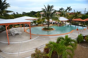 Un área de piscina con sillones de descanso y una palmera.