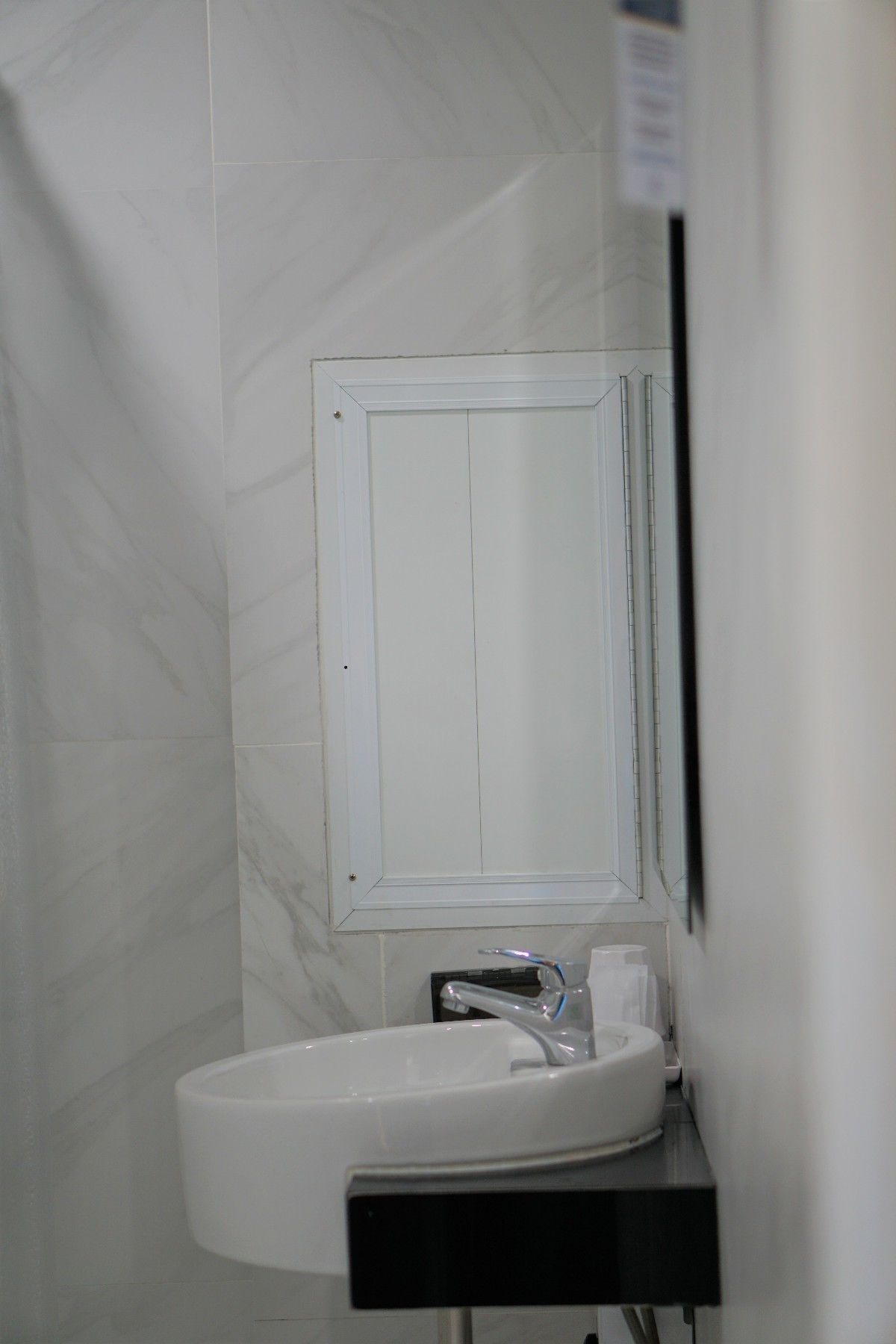 A bathroom with a white sink, a mirror, and a shower area.