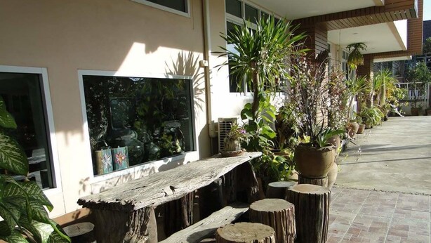A patio area with a wooden bench, potted plants, and a large window. - Klangmuang River Home (Phetchabun)