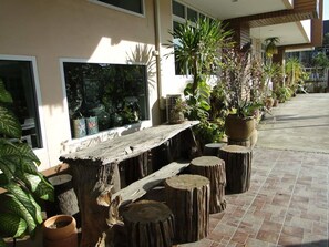 A patio area with a wooden bench, potted plants, and a large window. - Klangmuang River Home (Phetchabun)
