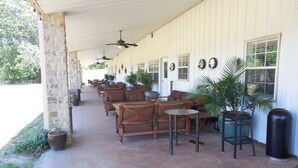 Un patio couvert avec des meubles d’extérieur, des ventilateurs de plafond et des plantes en pot.