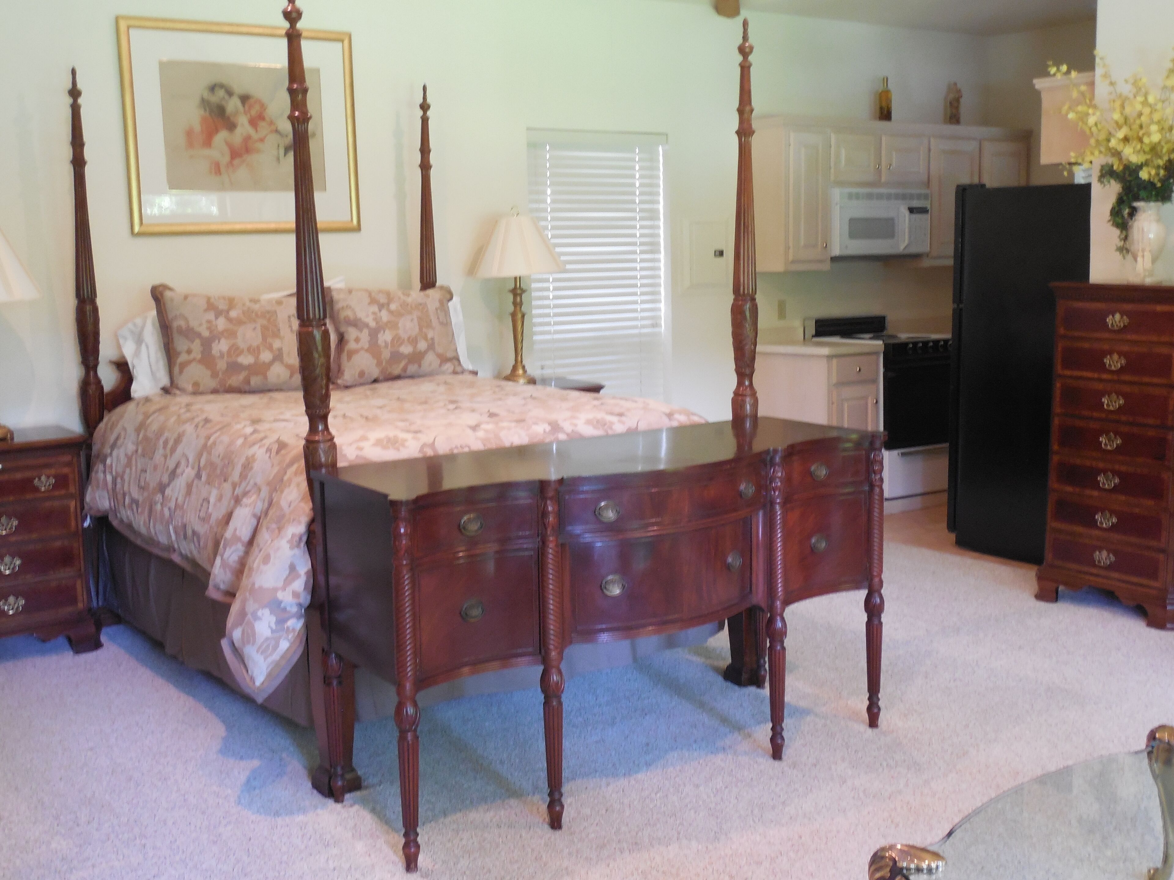 A bedroom with a four-poster bed, a dresser, and a nightstand.