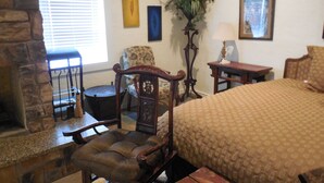 Une pièce confortable avec une cheminée, un lit, une chaise, une table et une fenêtre avec des stores.