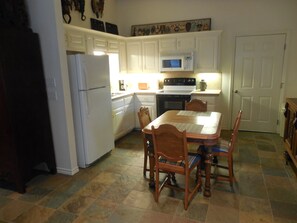 Kitchen area with refrigerator, microwave, and dining table.