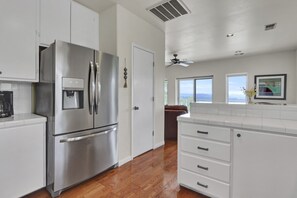 A modern kitchen with stainless steel appliances, white cabinetry, and a wooden floor. - Recently Renovated, Secluded Spot for a romantic rendezvous! Hot Tub, Fire pit (Wimberley)