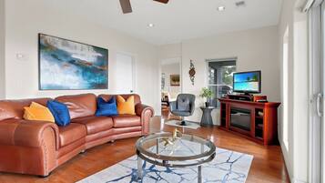 A modern living room with a leather sofa, a glass coffee table, and a television.