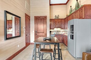 Una cocina con armarios de madera, un refrigerador y una mesa de comedor con sillas.