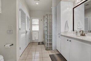 A bathroom with a toilet, a sink with a mirror, and a shower area.