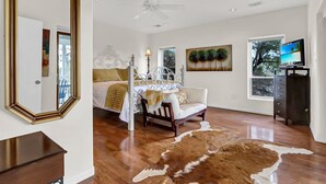 Une chambre à coucher comprenant un lit, une chaise, un bureau, un miroir, une télévision et un tapis en peau de vache.