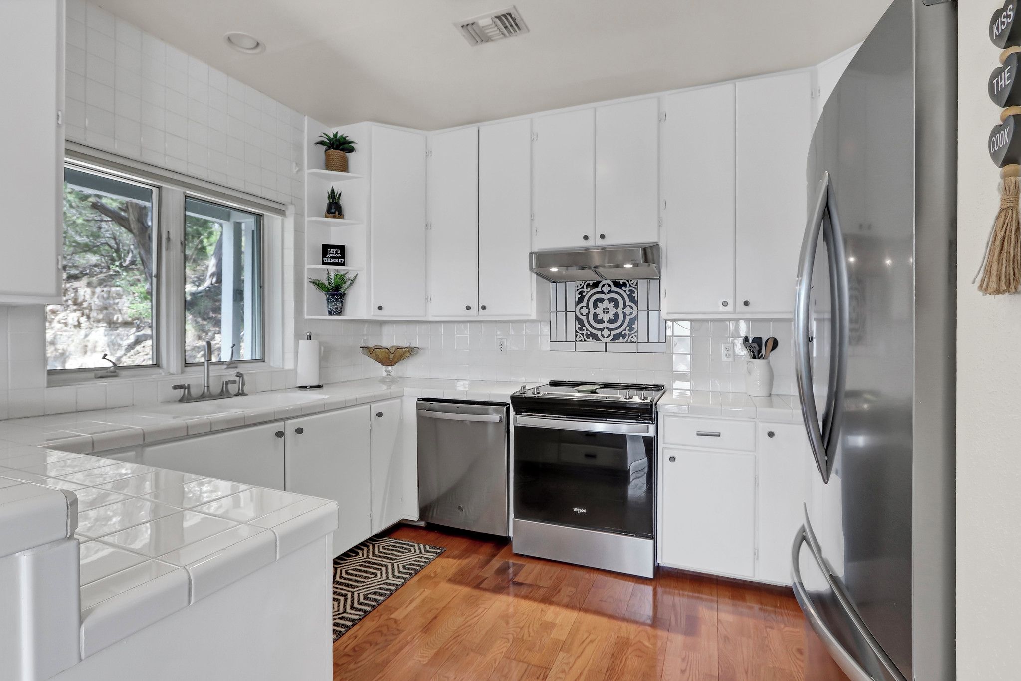 A modern kitchen with white cabinetry, a stainless steel refrigerator, a built-in oven, and a dishwasher.