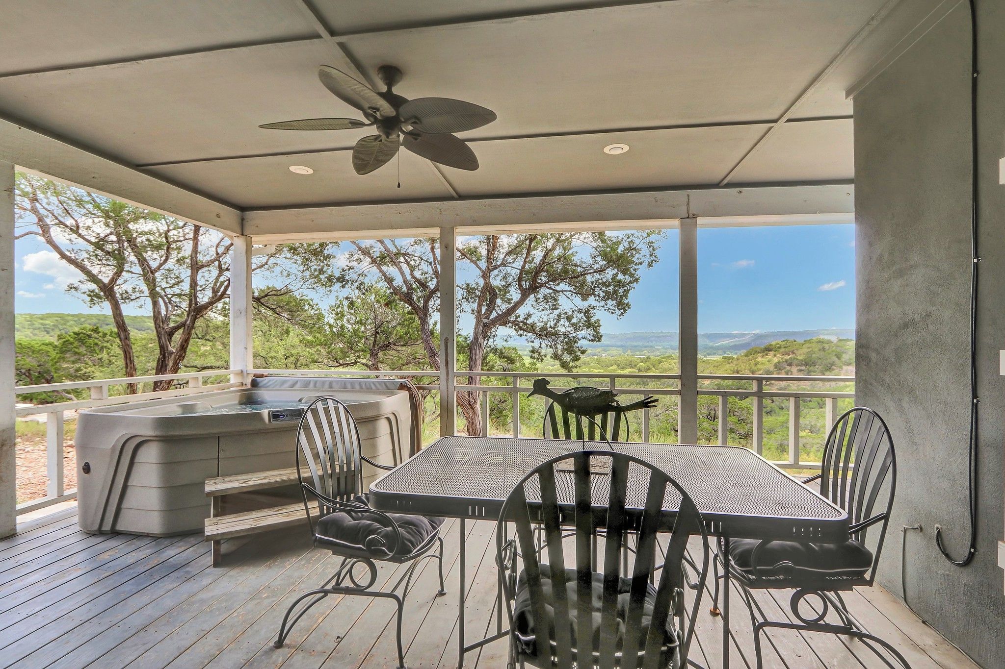 Une terrasse extérieure avec un jacuzzi, une table et des chaises, offrant une vue sur un paysage magnifique.