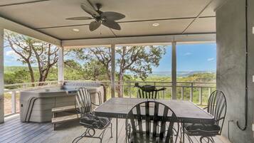 Une terrasse extérieure avec un jacuzzi, une table et des chaises, offrant une vue sur un paysage magnifique.
