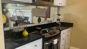 A kitchen with white cabinets, a black countertop, stainless steel appliances, and a tiled floor. - Spacious - Private 2 brs, 2 baths (Charleston)