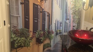 A narrow hallway with a mural of a street scene, a red bowl sink, and a wall-mounted light fixture. - Spacious - Private 2 brs, 2 baths (Charleston)