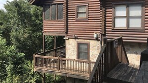 A log cabin with a stone foundation, a wooden deck, and a small outdoor seating area. - THE ONLY THING MISSING  YOU!Hot tub,air hockey,pool,no animals no smoking sleep6 (Pigeon Forge)