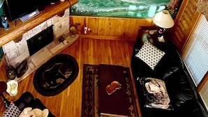 A cozy room with a wooden ceiling, a fireplace, a TV, and a large window with a mural of a bear and a puppy. - THE ONLY THING MISSING  YOU!Hot tub,air hockey,pool,no animals no smoking sleep6 (Pigeon Forge)