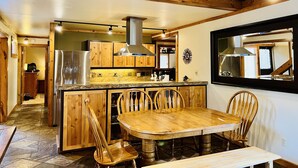Eine Küche mit Holzausbau, einem Edelstahlkühlschrank, einem Holzespeisesatz und einem großen Spiegel an der Wand.