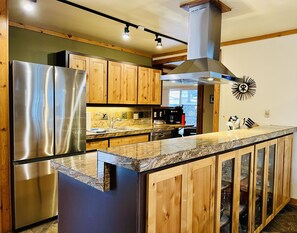 A modern kitchen with wooden cabinets, stainless steel appliances, and a granite countertop. - Cozy, smoke-free, 2 BD 2 BA home, 6 adult MAX, 6 SHARC passes, steps to village (Sunriver)