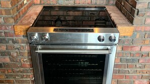 Eine Küche mit einem Edelstahlkochfeld und -backofen, Ziegelwänden und einer Holzarbeitsplatte.