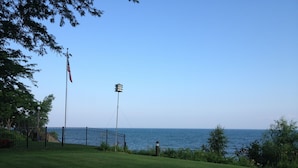 Eine begrünte Fläche mit Blick auf das Meer, ein Fahnenmast mit einer amerikanischen Flagge und eine Straßenlaterne.
