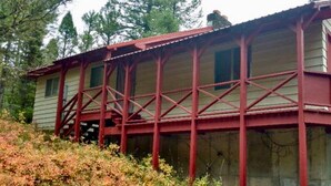 A wooden cabin with a red metal framework, a single window, and a porch. - Secluded Summer or Winter Getaway! (Island Park)