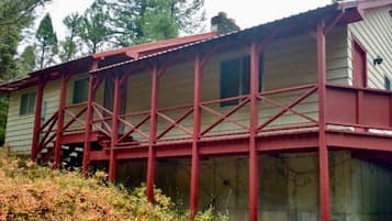 A wooden cabin with a red metal framework, a single window, and a porch.