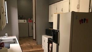 A kitchen with a white countertop, a refrigerator, a microwave, and a washing machine. - Secluded Summer or Winter Getaway! (Island Park)