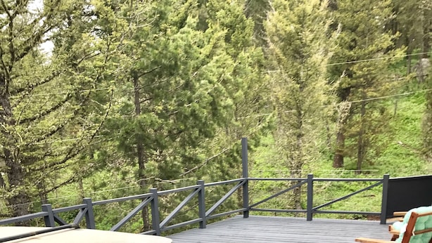 A wooden deck with a hot tub, a wooden table, and two chairs. - Secluded Summer or Winter Getaway! (Island Park)