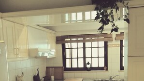 Una cocina con armarios blancos, encimera de granito, un fregadero y una ventana con persianas.