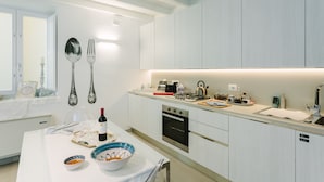 A modern kitchen with white cabinetry, a built-in oven, and a countertop with various appliances. - Charming Sea-View Hideaway in Ortigia. Comfort, Style and Unforgettable Sunsets. (Siracusa)