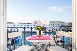 A balcony with a table and chairs, overlooking a marina with boats and buildings. - Sea-View Loft in Ortigia. Comfort, Style and Unforgettable Sunsets. (Siracusa)