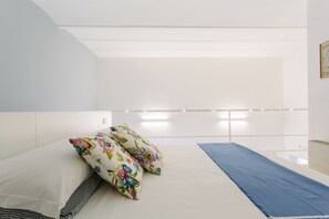 A modern bedroom with a bed, pillows, and a blue bed runner. - Sea-View Loft in Ortigia. Comfort, Style and Unforgettable Sunsets. (Siracusa)