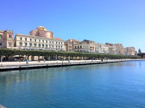 A waterfront promenade with historic buildings, a clear sky, and a calm river. - Sea-View Loft in Ortigia. Comfort, Style and Unforgettable Sunsets. (Siracusa)